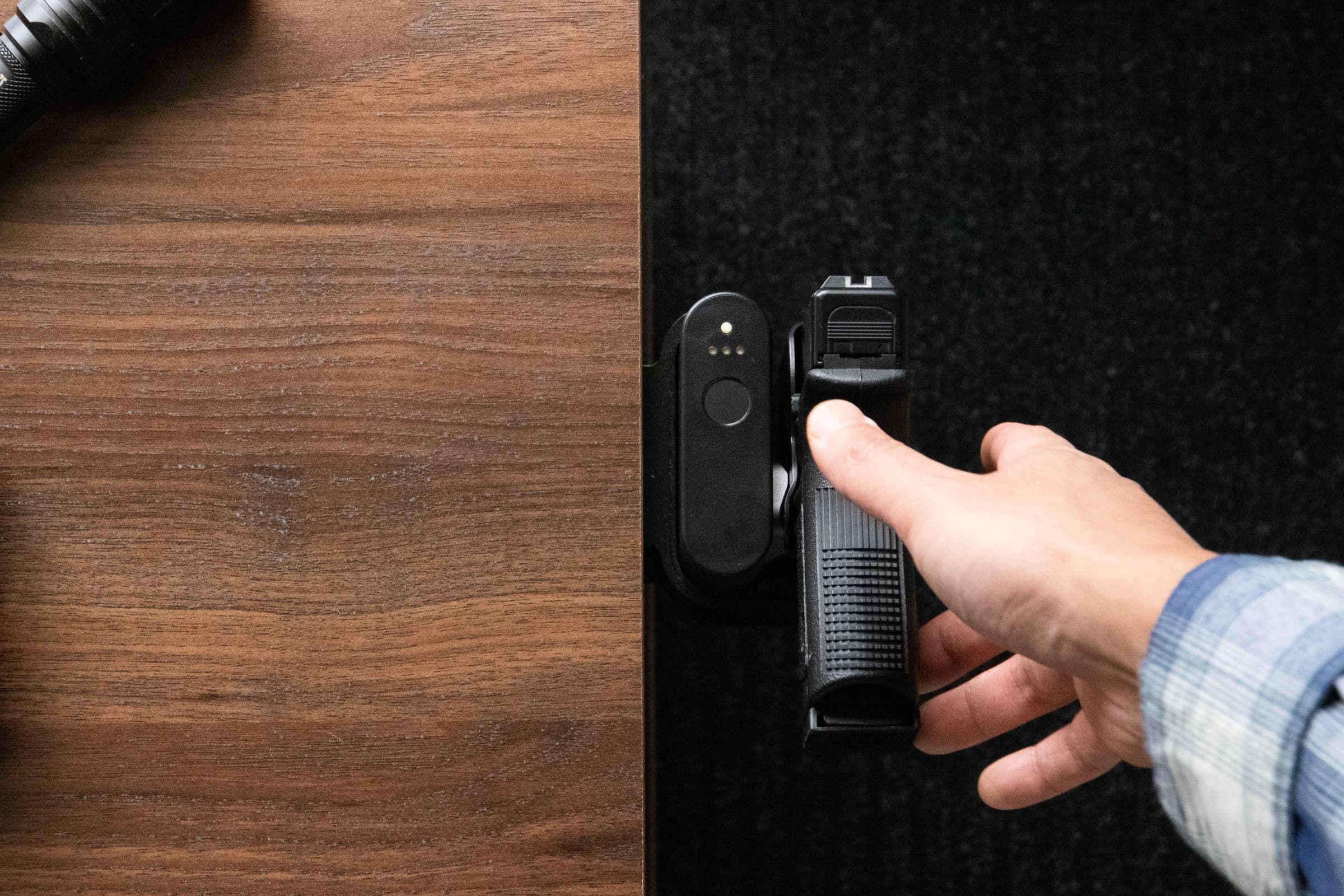 A thumb resting on the Reach 2S fingerprint sensor as the hand closes around the pistol grip